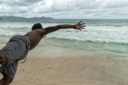 Black man jumping in water in seychellesの写真素材