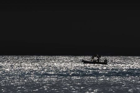 fishing boat silhouette at sunset in mediterranean seaの写真素材