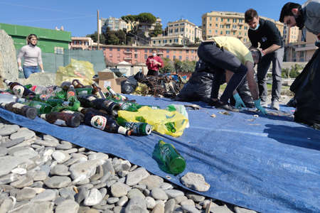 GENOA, ITALY - FEBRUARY 28 2021 - Young volunteers collect plastic and trash at the beach. The problem of plastic and litter on shorelines is becoming unsustainable. Fortunately, groups of volunteers are organizing for the cleanup. An example to follow.のeditorial素材