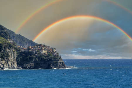 Manarola cinque terre pictoresque village liguria italy with double rainbow sky backgroundの写真素材