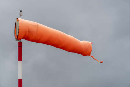 orange sock wind indicator on cloudy sky backgroundの写真素材