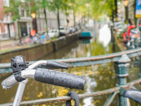 A bicycle handlebar on canals of Amsterdam view on rainy dayの写真素材