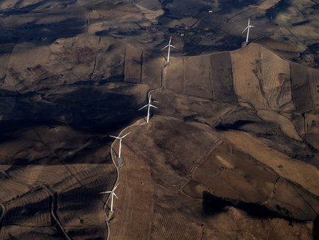 Many Windmill wind turbines near Etna volcano in Sicily and farmed fields aerial view from airplane