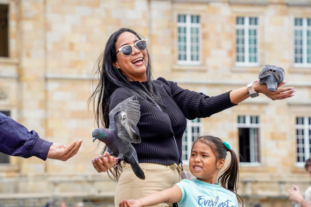 BOGOTA, COLOMBIA - JULY 3 2024 - Many tourist feeding pigeons with corn at Plaza de Bolivar during a sunny dayのeditorial素材