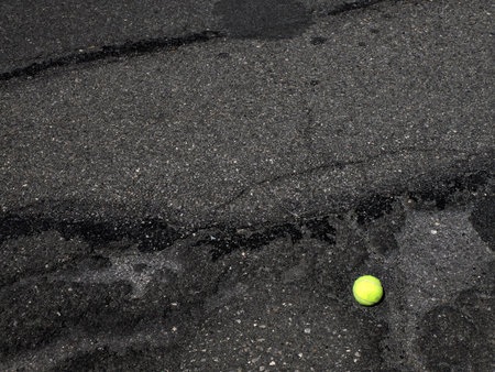 An abandoned tennis ball on the asphalt of the streetの写真素材