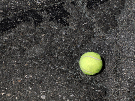 An abandoned tennis ball on the asphalt of the streetの写真素材