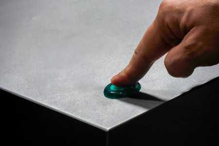 finger pressing green illuminated button on metal isolated detail close up