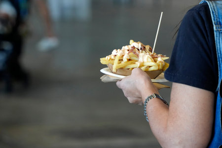 hands holding french fries plate with sauces detail