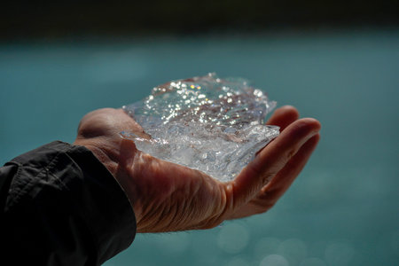 Hand holding piece of ice fallen from the Spegazzini glacier los glaciares park Patagonia Argentinaの写真素材