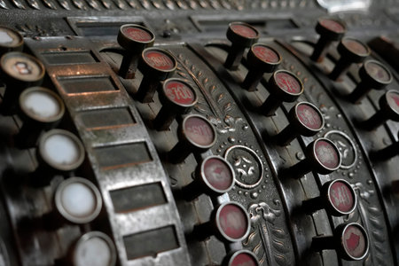 A Vintage mechanical cash register, featuring metal keys and glass or plastic inserts typical of...