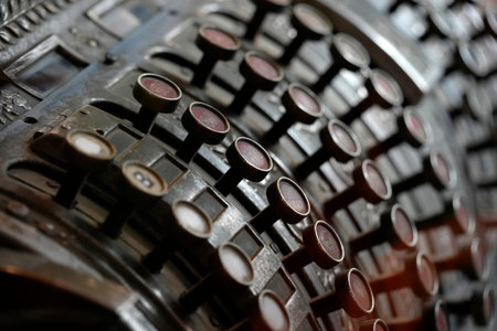 A Vintage mechanical cash register, featuring metal keys and glass or plastic inserts typical of...
