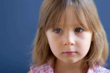 Portrait of serious little girl over blue backgroundの写真素材