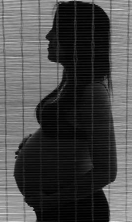 Pregnant woman in shadow with curtain effectの写真素材