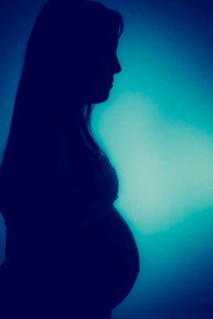 Pregnant woman in shadow with blue effectの写真素材