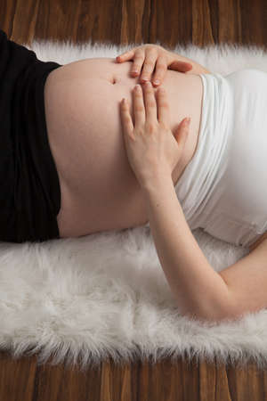 Pregnant woman with hands over her stomachの写真素材