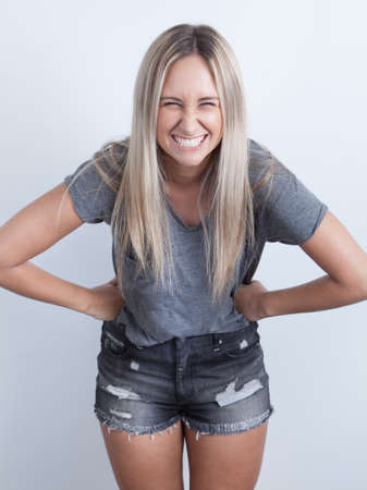 Portrait of a young blond woman smilling against a white background