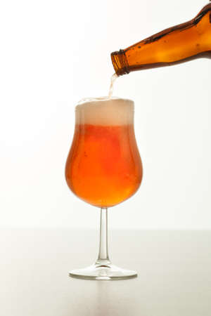 Beer pouring into glass on a white backgroundの写真素材