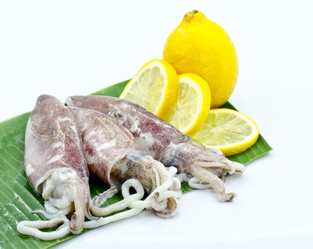 Fresh cuttle fish decorated with lemon stacked on banana leaf.の写真素材