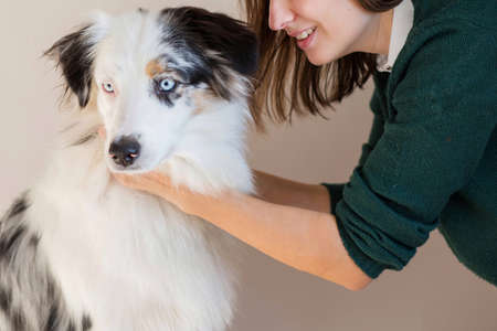 Smiling woman in green jacket holding Australian shepherdの写真素材