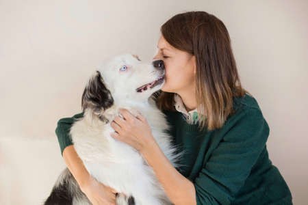 European woman in green jacket kissing Australian shepherdの写真素材