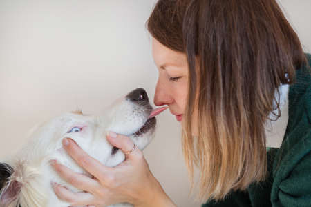 European woman in green jacket kissing Australian shepherdの写真素材