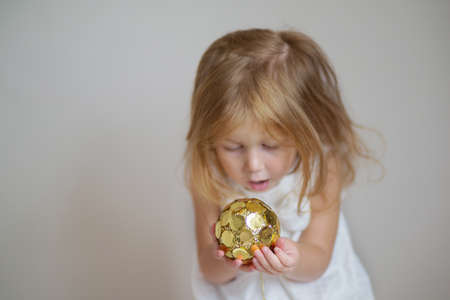 Redhair girl with gold christmas ornament on light gray backgroundの写真素材