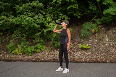 active seniors woman in fitness suit holding thermoの写真素材