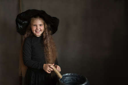 Happy girl in halloween witch costume on gray backgroundの写真素材
