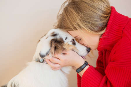 European woman in red jacket with Australian shepherd