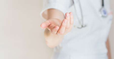 Woman doctor giving hand on light gray backgroundの写真素材