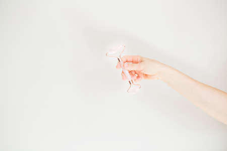 European woman hand holding jade roller on light gray backgroundの写真素材