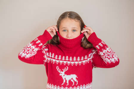 Girl in Christmas sweater on light grey backgroundの写真素材