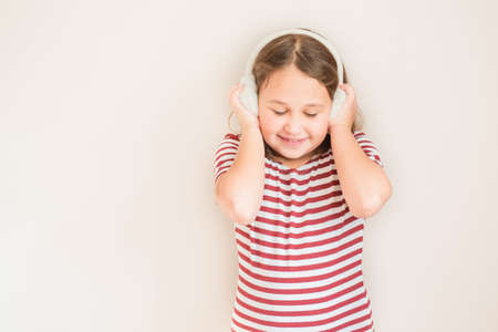 Smiling girl in red and white striped t-shirt with fur earmuffsの写真素材