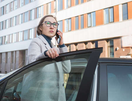 Fashion business woman in glasses get out of the car