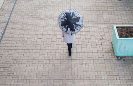 woman in the coat with umbrella walking in the autumn cityの写真素材