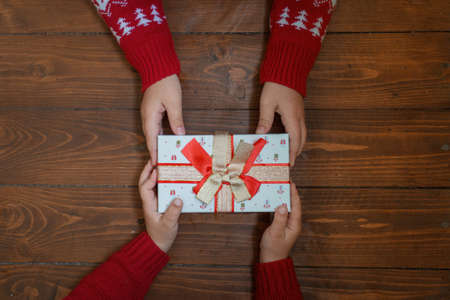 gift in two kids hands on dark wooden background