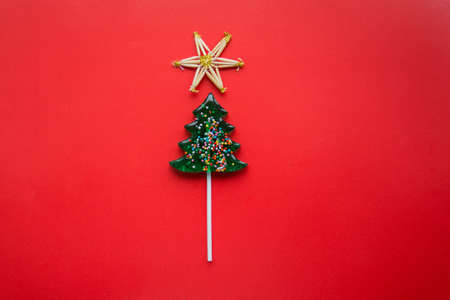 Christmas tree lollipop on red background with straw star on topの写真素材