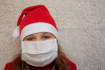 Girl in Christmas sweater and santa hat in medical maskの写真素材