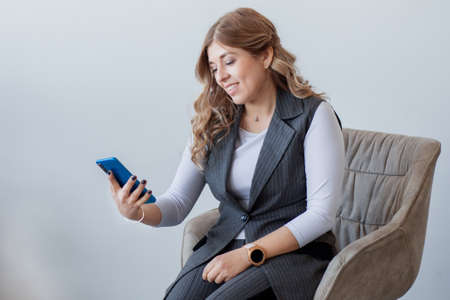 Blonde European businesswoman sitting and looking in phone