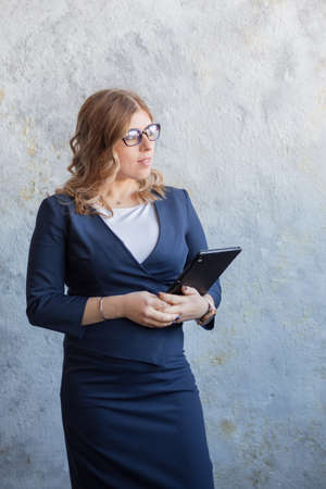 Blonde European businesswoman standing with tablet in glassesの写真素材