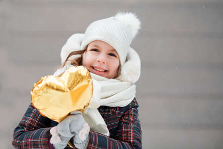 Little girl with golden heart balloon. Valentine day.の写真素材