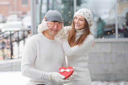 Young man surprised his girlfriend with heart gift box in the cityの写真素材