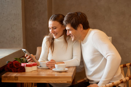 Young couple sitting in caffe with coffee, heart gift box. Online shoppingの写真素材