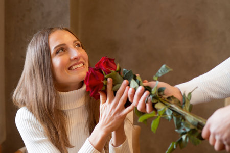 Man surprised girlfriend in caffe with bouquet of rosesの写真素材