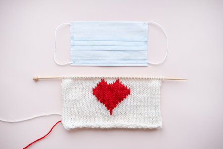 knitted red heart. wooden knitting needles. face mask. Valentine.