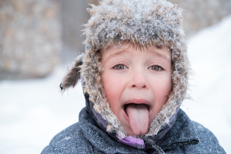 Little cute boy in winter hat. Show tongueの写真素材
