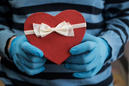 Mans hands gloves hold red heart gift box. Valentine day.の写真素材