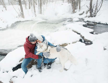 Couple hugging and sitting with siberian husky dog in winter. Valentine day.