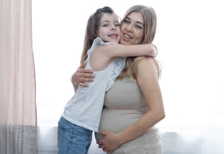 Caucasian happy little girl with blonde pregnant mother. hugs Together.の写真素材