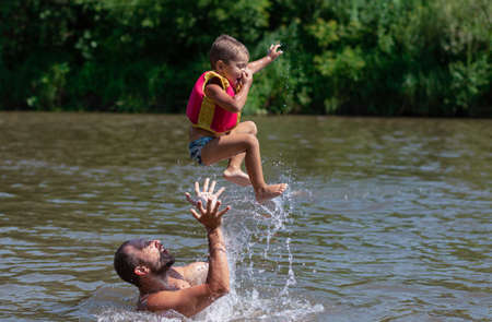 Father and son swim and jump in the waterの写真素材